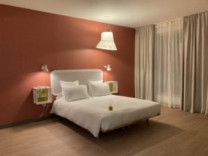 Chambre adaptée avec grands espaces autour du lit, au centre de l'image un lit avec draps blancs 